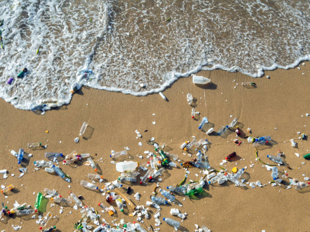 Waves pushing plastic waste to the beach Plastic waste polluting the beach, mostly bottles that are pushed and attracted to the waves microplastics stock pictures, royalty-free photos & images